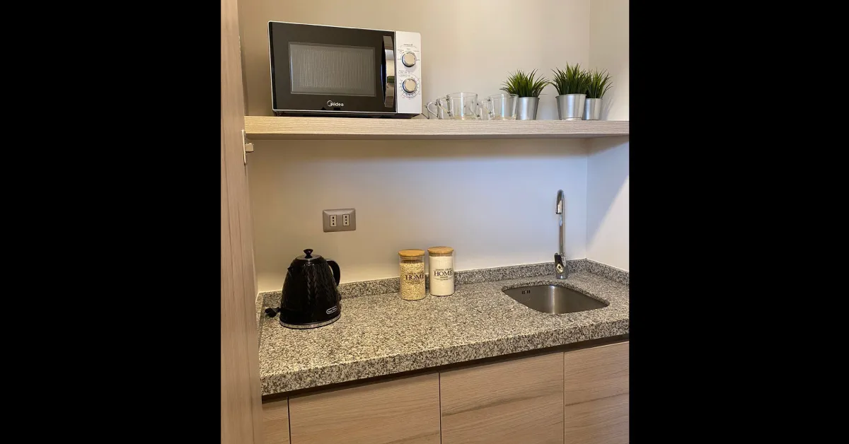 Kitchenette equipada con cubierta de granito gris mara en Oficinas Parque Urbano, Viña.