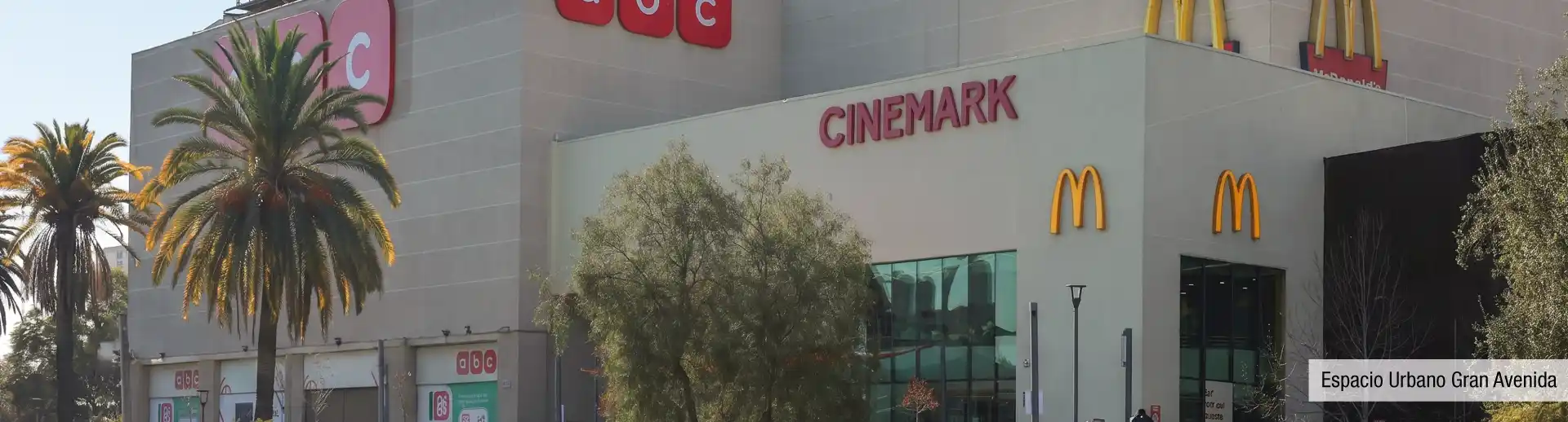 Fachada de Espacio Urbano Gran Avenida cerca de Edificio Santa Corina en La Cisterna, destacando cines y tiendas retail.