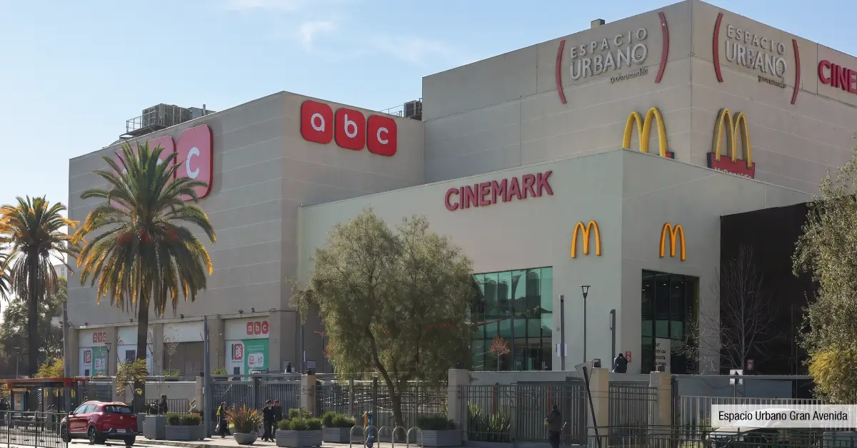 Fachada de Espacio Urbano Gran Avenida cerca de Edificio Santa Corina en La Cisterna, destacando cines y tiendas retail.